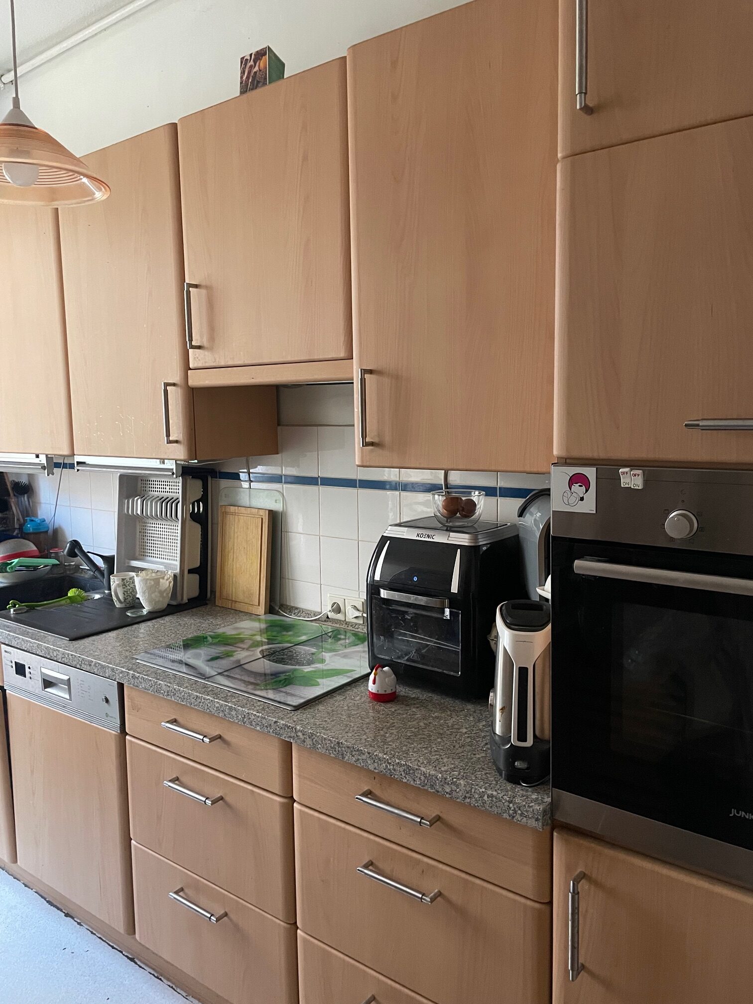 Moderne, holzfarbene Küche mit Küchengeräten und Arbeitsplatte, helle Wände und dezente Beleuchtung.